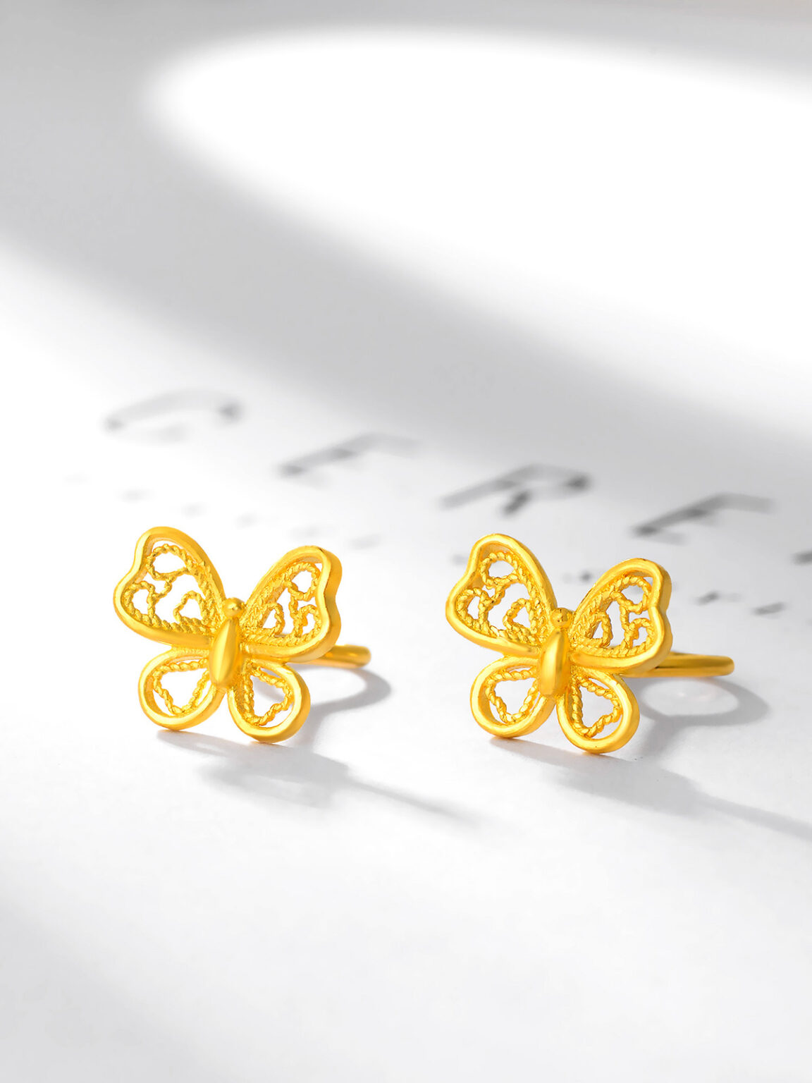 Gold butterfly stud earrings displayed on a bright white background with soft shadows.