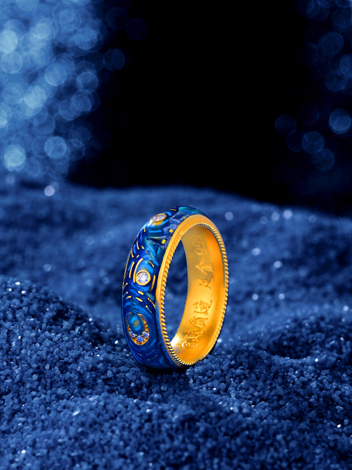 Gold ring with blue gemstone details photographed on dark blue textured fabric.